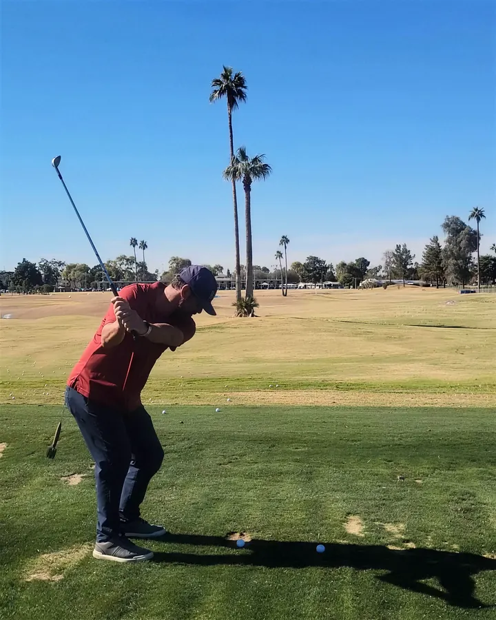 Pat at the top of his backswing on the grass range at Dobson Ranch, palms beyond