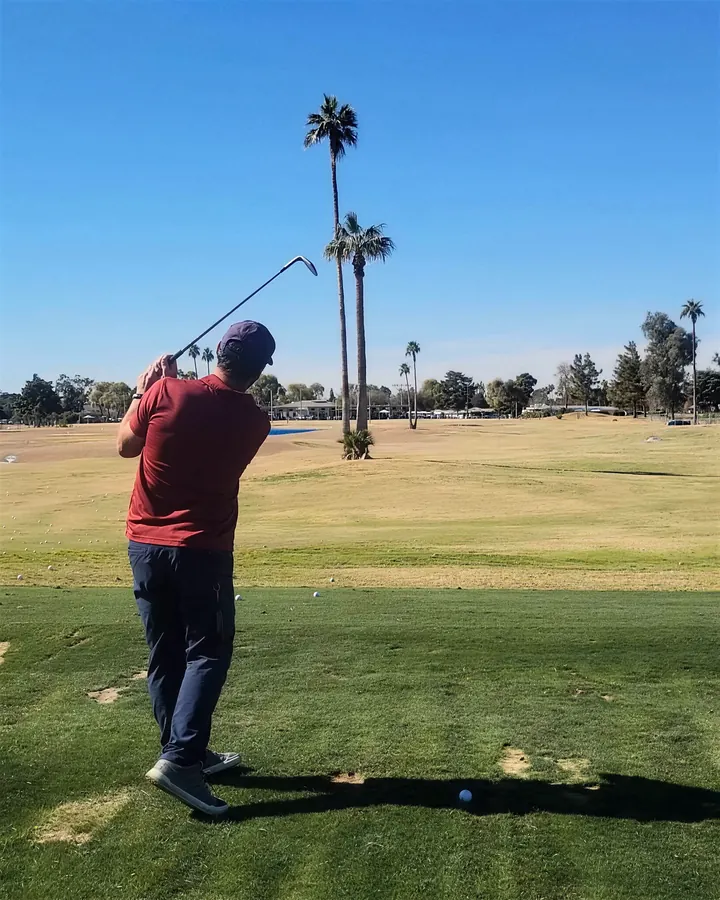 Pat holding his finish on the grass range at Dobson Ranch, palms beyond